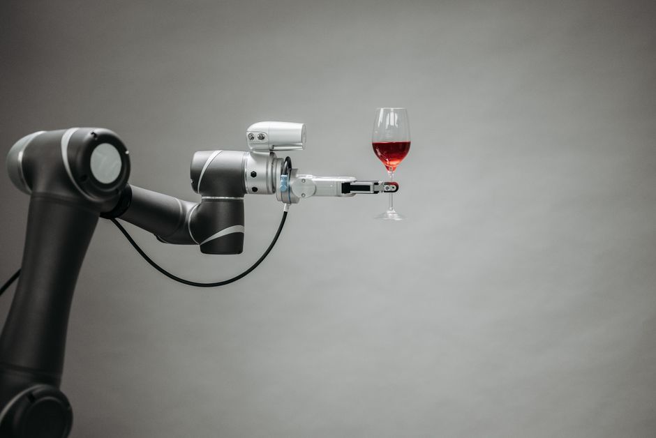 A modern, metallic robotic arm precisely holding a delicate ice cream cone, illustrating the intersection of technology and the food service industry.