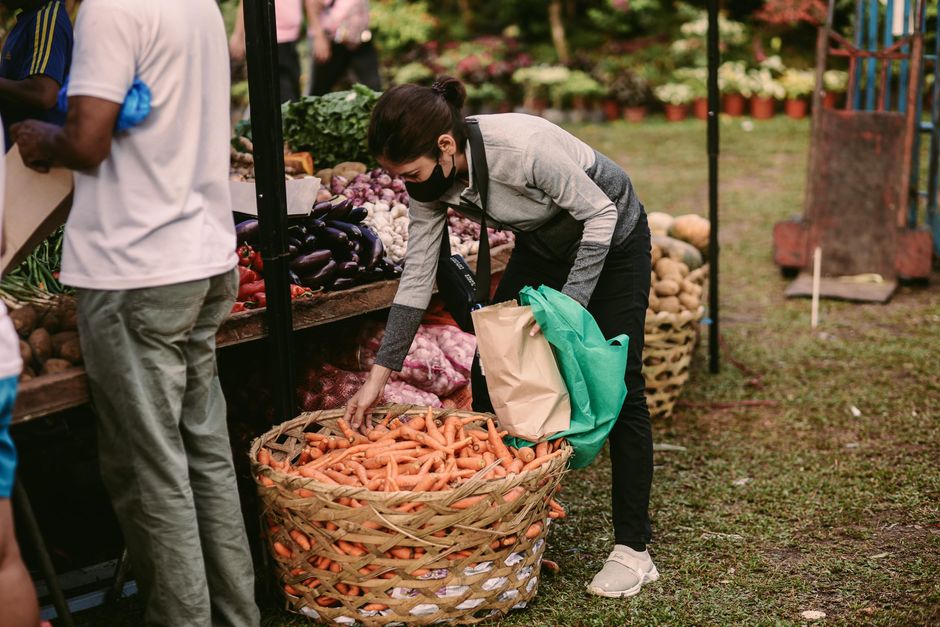 A person carefully selecting fresh, vibrant vegetables from a stall at a local farmers' market, symbolizing smart, healthy, and cost-effective shopping.