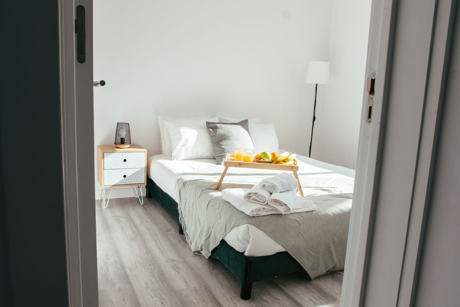 A beautifully prepared guest bedroom with a thoughtful welcome basket containing treats and local goods placed on a neatly made bed, signifying hospitality.